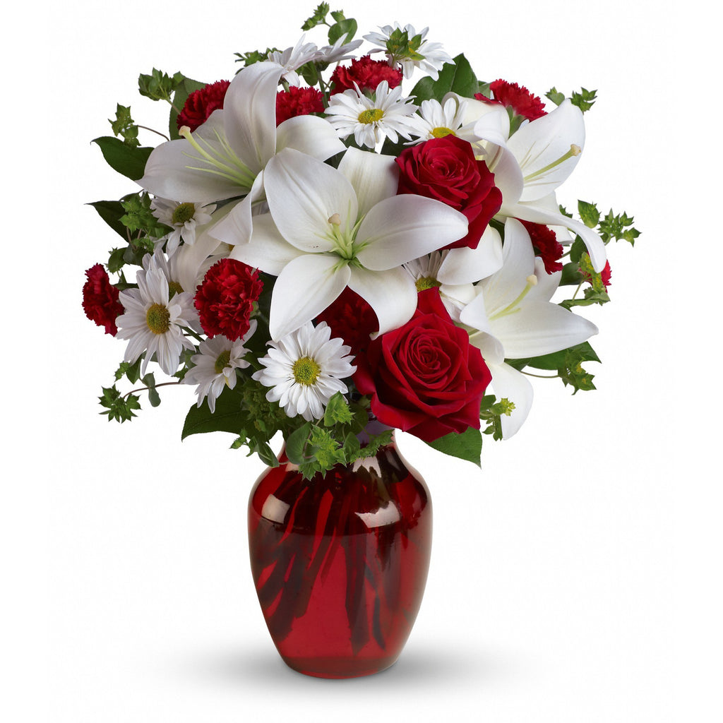 All red and white flowers with beautiful lilies, roses, carnations and daisies come perfectly designed in a red vase ready to show your love!   Vase and/or flower variety will vary depending on availability. Arrangement will be as close as possible, but may not be exact.