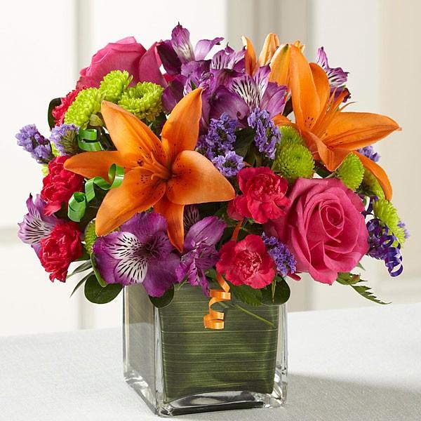 It's a party all inside a stylish square vase complete with curly ribbon accents. Bright orange, hot pink, lime green, and orange assorted flowers.   Vase and/or flower variety will vary depending on availability. Arrangement will be as close as possible, but may not be exact.