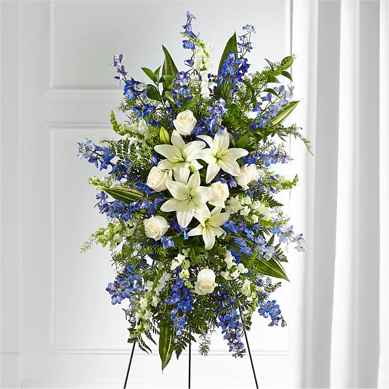 A beautiful standing spray with assorted greenery, bright blue delphinium and assorted white flowers.

Flower variety will vary depending on availability. Arrangement will be as close as possible, but may not be exact.