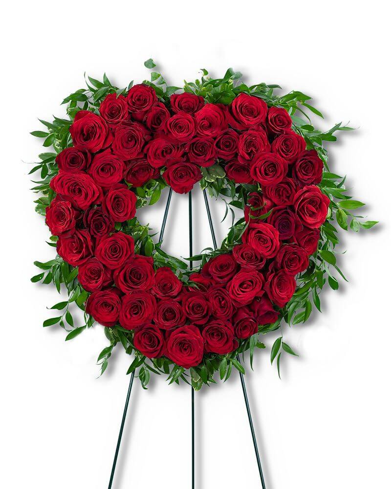 Heart-shaped wreath made of red roses  and accented with greenery on a white background