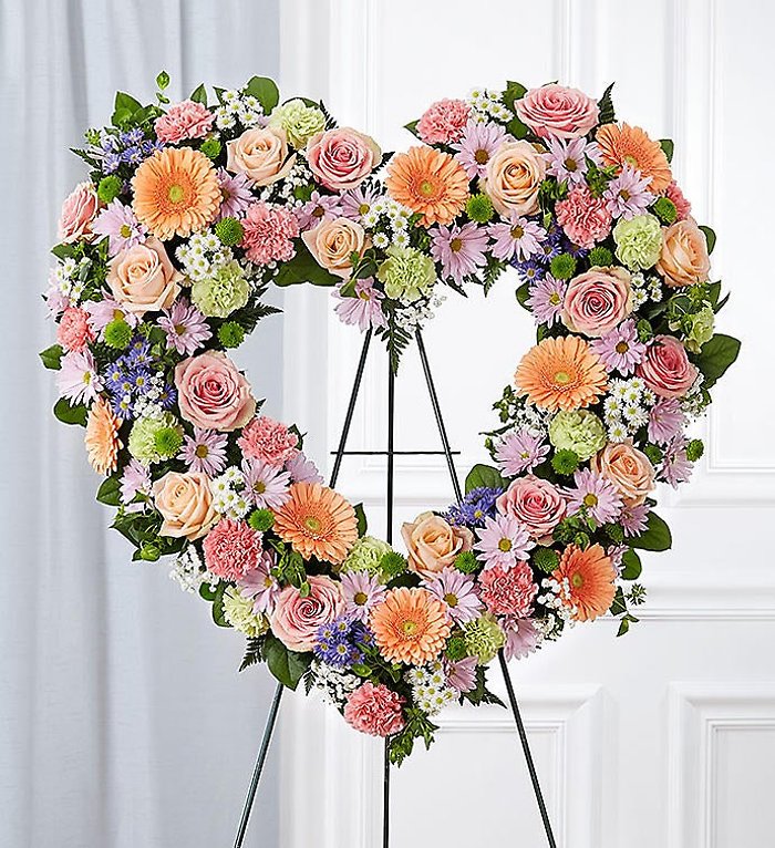 Colorful floral heart wreath in pastel colors on a stand against a white background