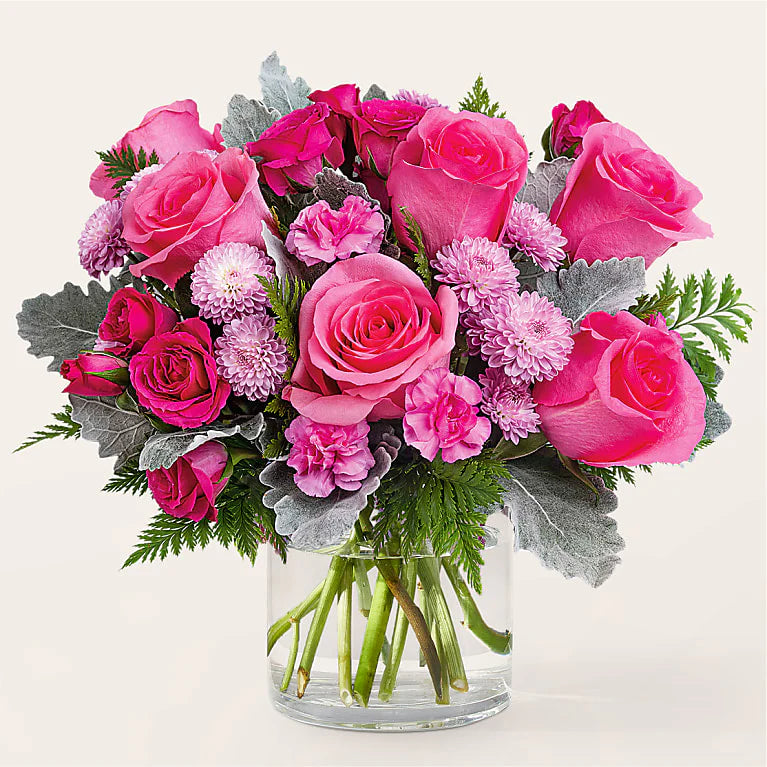 A clear cylinder vase filled with greenery, hot pink roses, hot pink miniature roses, pink miniature carnations and lavender button mums. This arrangement is perfect for someone who loves pink.

Flower variety will vary depending on availability. Arrangement will be as close as possible, but may not be exact.