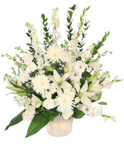 A floral arrangement with white flowers and green foliage in a white container.
