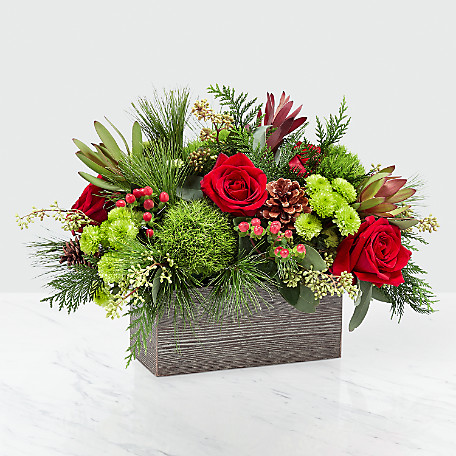 A rectangle wood box filled with evergreens and assorted red and green flowers.   Box and/or flower variety will vary depending on availability. Arrangement will be as close as possible, but may not be exact.