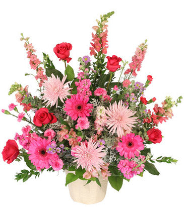 A  traditional style sitting spray created out of  vibrant pinks and accented with pastel lavender blooms is a stunning combination of flowers. Snapdragons, roses, carnations, and more.   Container and/or flower variety will vary depending on availability. Arrangement will be as close as possible, but may not be exact.