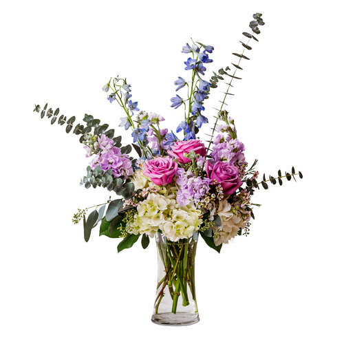 A whimsical design of white, lavender, and blue flowers accented with eucalyptus in a clear glass vase.  Vase and/or flower variety may vary depending on seasonal availability. Arrangement will be as close as possible, but may not be exact. 