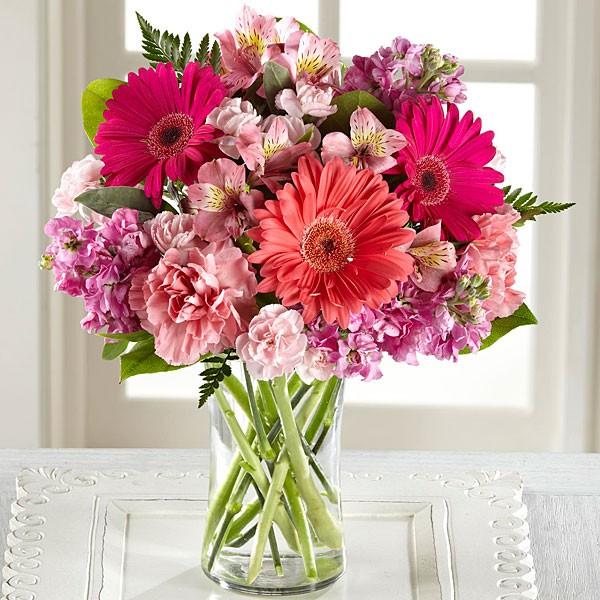 Pink gerbera daisies, pink alstromeria, pink stock, pale pink carnations and mini carnations in a clear glass cylinder vase.  Vase and/or flower variety will vary depending on availability. Arrangement will be as close as possible, but may not be exact.