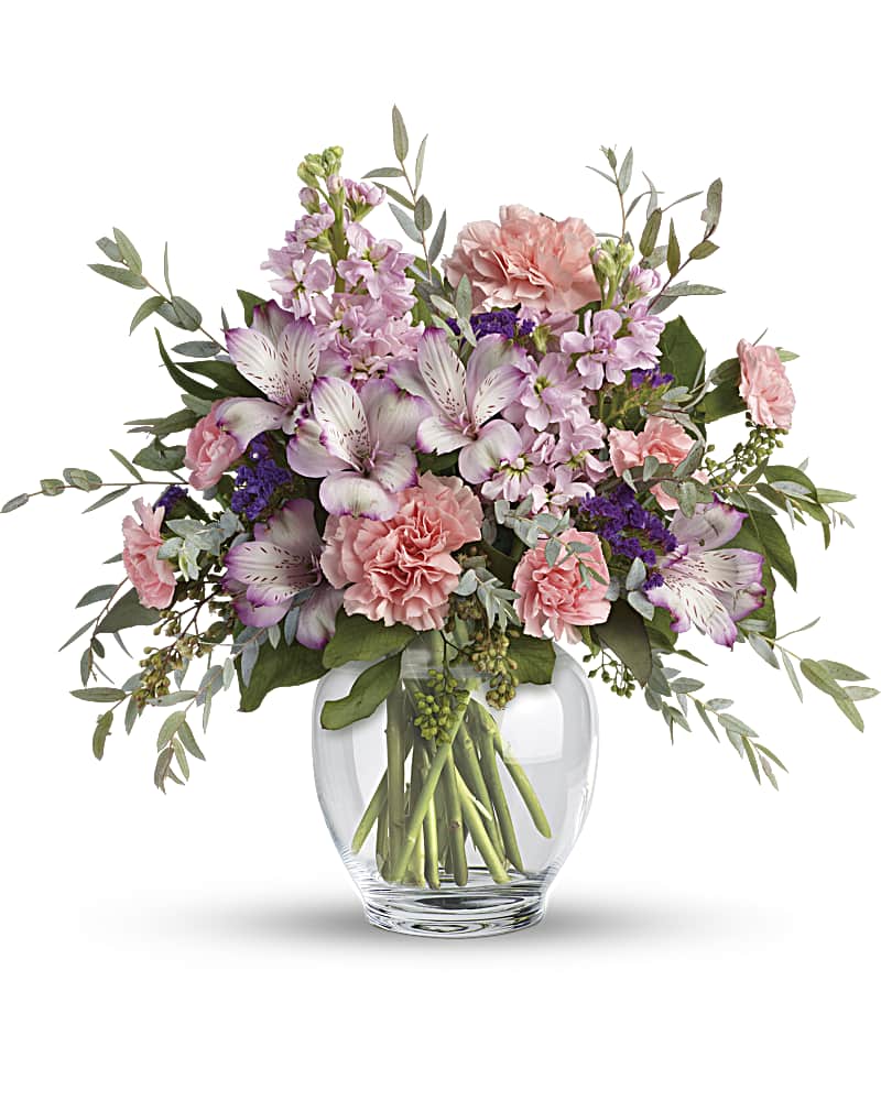 A mix of pink, lavender, and purple assorted flowers in a clear glass vase.   Vase and/or flower variety will vary depending on seasonal availability. Arrangement will be as close as possible, but may not be exact. 