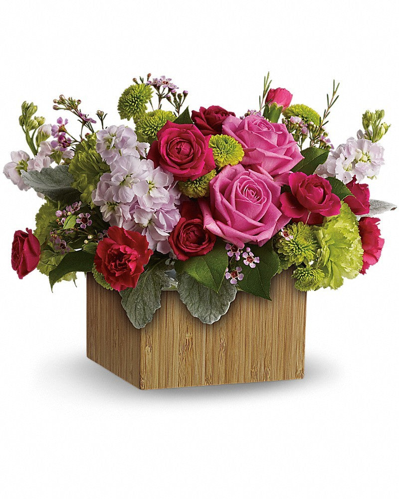 A wood square  box filled with blooms in pinks and greens with flowers such as roses, stock, button mums and miniature roses.  Box and/or flower variety will vary depending on availability. Arrangement will be as close as possible, but may not be exact.
