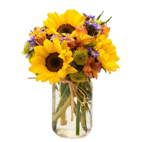 A mason jar filled with sunflowers and assorted accent flowers.  Vase and/or flower variety will variety on seasonal availability. Arrangement will be as close to possible, but may not be exact. 